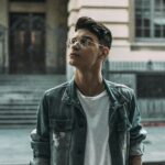 A fashionable man with glasses looks upwards in an urban setting in São Paulo, Brazil.